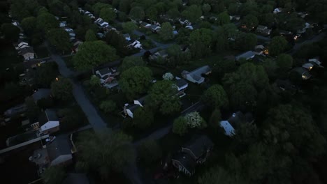 one family houses and garden during dark night in american city neighborhood. green trees in spring season. dusk scene. sleeping families in family friendy housing area. aerial top down flyover.