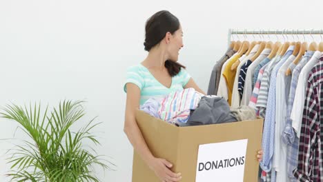 pretty asian brunette holding donation box full of clothes