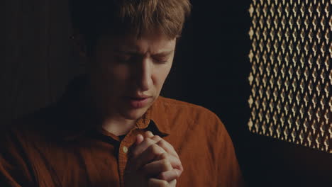 young female parishioner praying in confessional booth