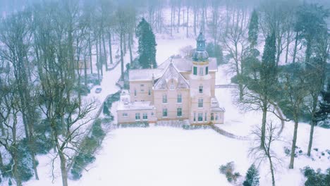 static aerial view of blizzard and snow capped mansion in rural netherlands