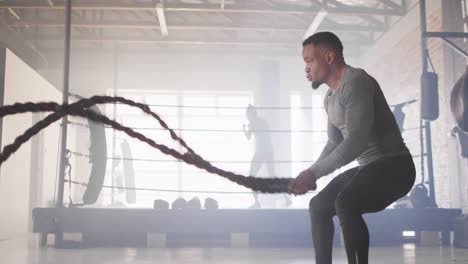 video de un hombre afroamericano en forma entrenando con cuerda en el gimnasio