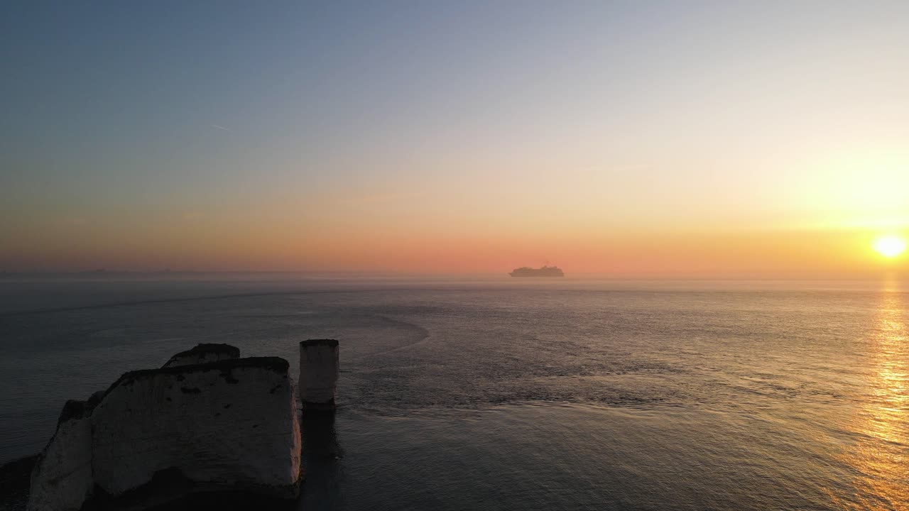 바다 위에 일몰에 화려한 하늘과 백그라운드에서 유람선, 오래 된 해리 바위 절벽, 영국