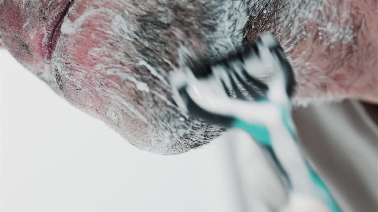 Close up of a man shaving his beard with a razor