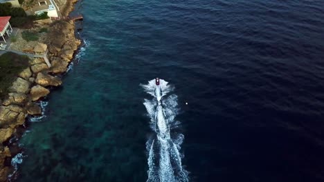 Aerial-view-dolly-in-tilt-down-of-a-jet-ski-on-the-shores-of-Jan-Thiel-Beach,-Curacao,-Dutch-Caribbean-island