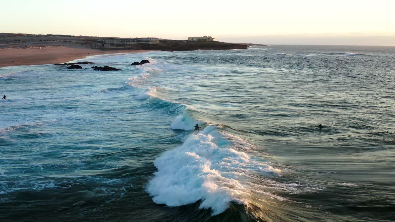 Sunset Drone shot of surfers catching waves on praia do guincho on Cascais - Sintra