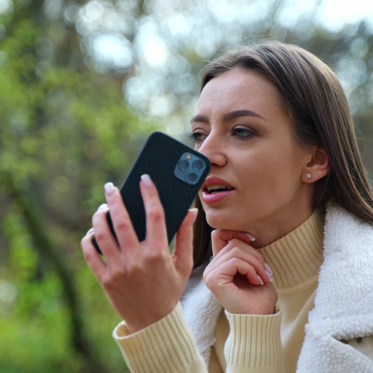 Beautiful young outdoor communication. Pretty lady with phone sitting in park