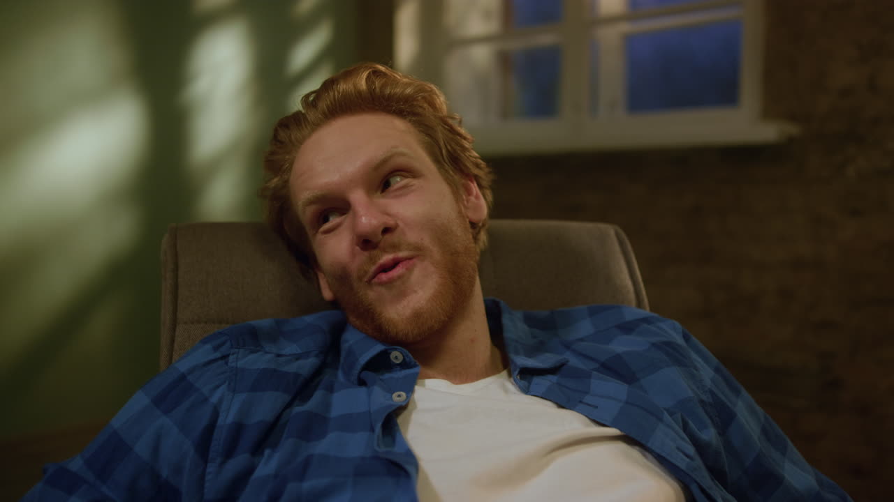 hombre alegre relajándose en su nuevo apartamento. hombre sonriente cayendo en el sillón.