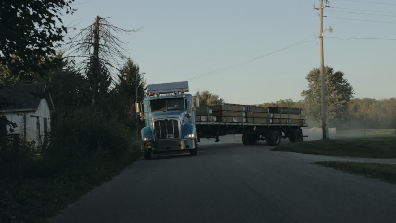 Peterbilt semi truck pulling out of yard and driving down the street front view in slow motion