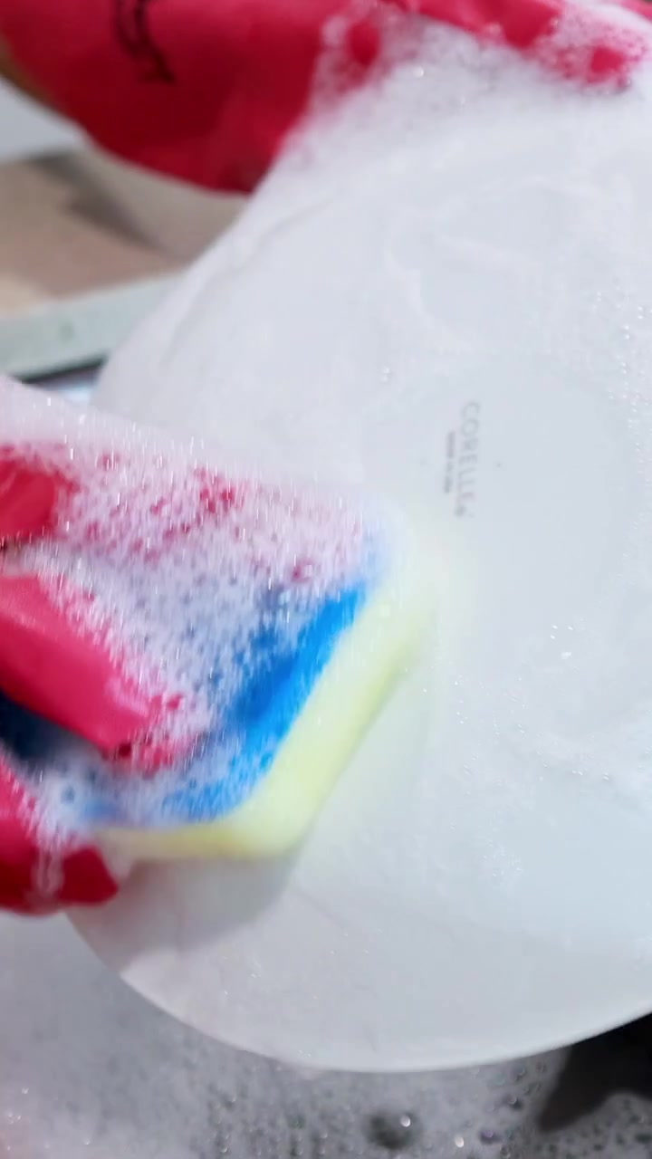 Person Wearing Pink Rubber Gloves Washing a White Plate