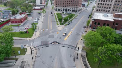 a descending drone shot approaches the lighted vehicle city sign and archway above saginaw street in flint, michigan at dusk in the summer