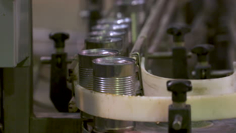 close up of aluminum cans moving along a production line in a canning factory