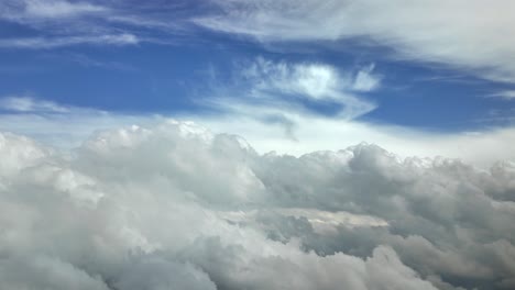 an aerial view taken from a jet cockpit while flying peacefully through a stormy sky full of white color cottony and stormy clouds under a blue sky. high-contrast, ultra-realistic shot. 4k