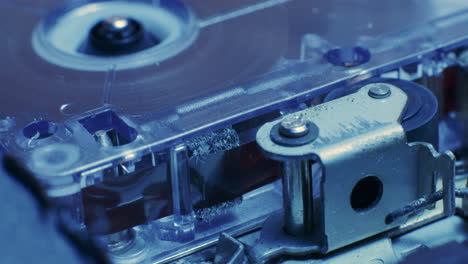 primer plano de la cinta de cinta grabadora de microcassette que se ejecuta a través del casete en luz azul fría