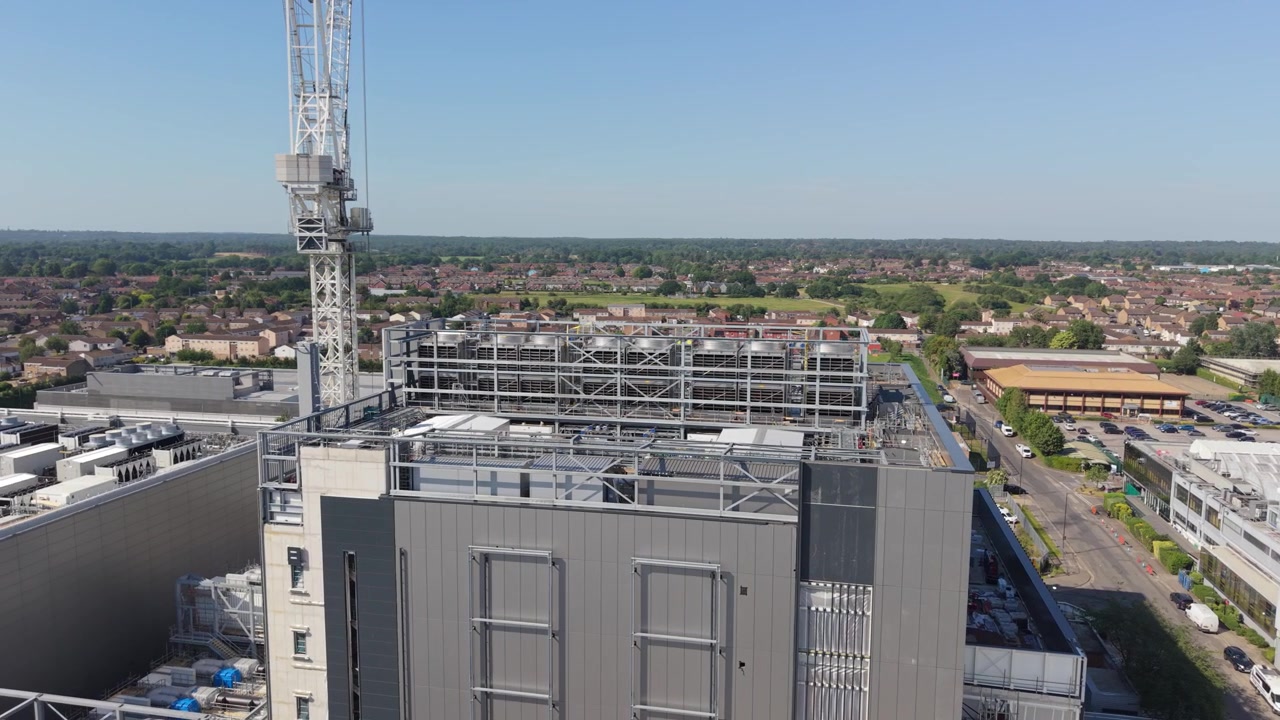 Costruzione di un grande edificio per data center. Una gru alta assiste nello sviluppo in un'area urbana. La moderna struttura è mostrata in una giornata luminosa e limpida, con dintorni residenziali