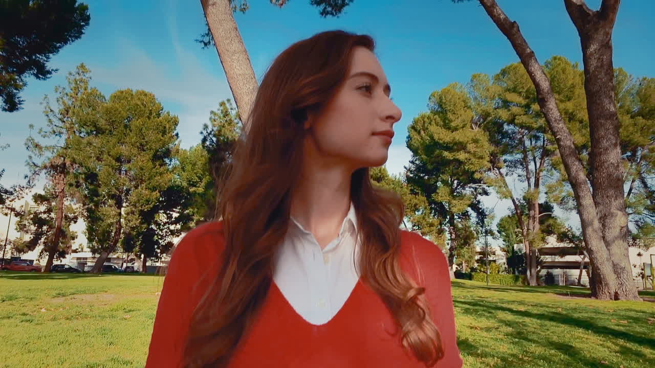 una feliz, atractiva, joven, mujer caucásica en el parque, gira la cabeza hacia la cámara y da una gran sonrisa y una gran risa