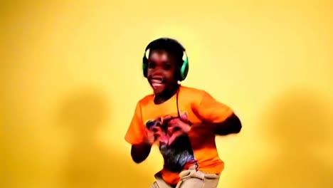 a young boy in an orange shirt is dancing with headphones on