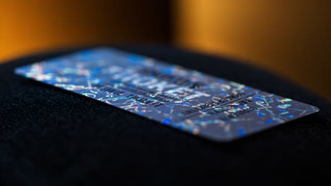 close-up view of a shimmering credit card resting on a soft surface, highlighting its holographic patterns and unique design features in two distinct frames