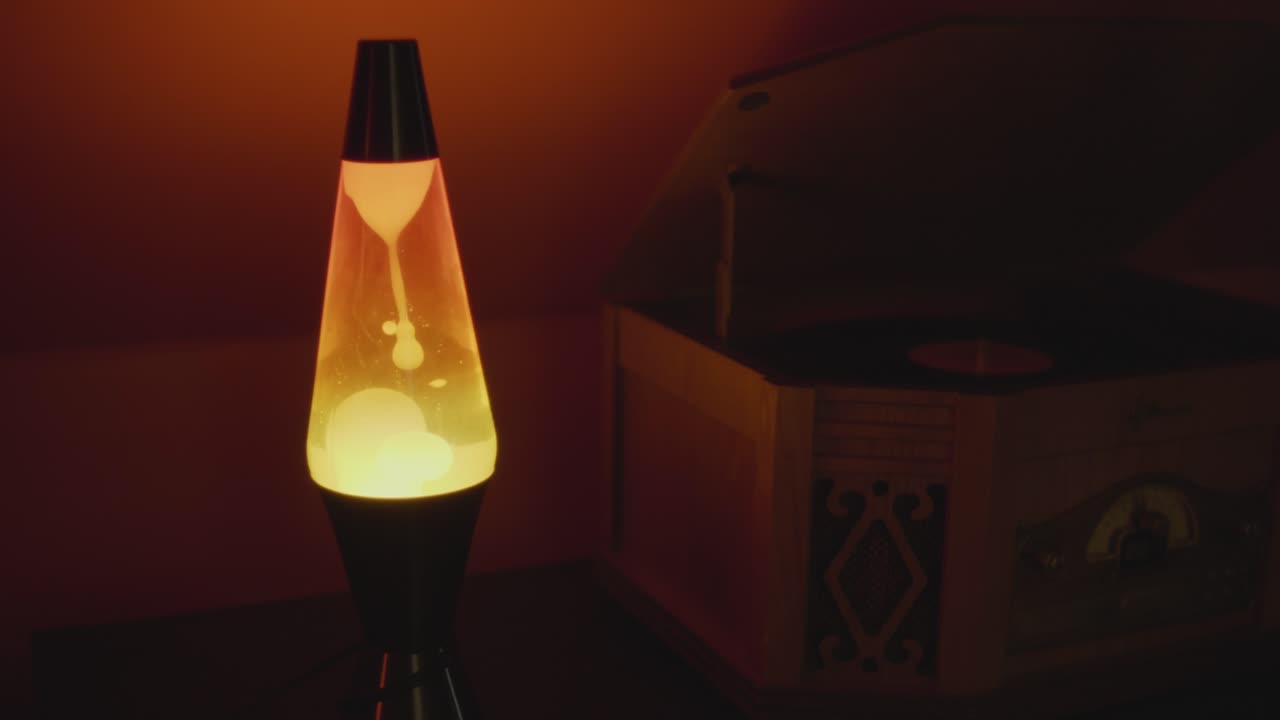 Close up of a vintage lava lamp in a warm and vintage setting. Orange lighting and bubbles create a retro atmosphere. Shot in 60 Frames for slow motion