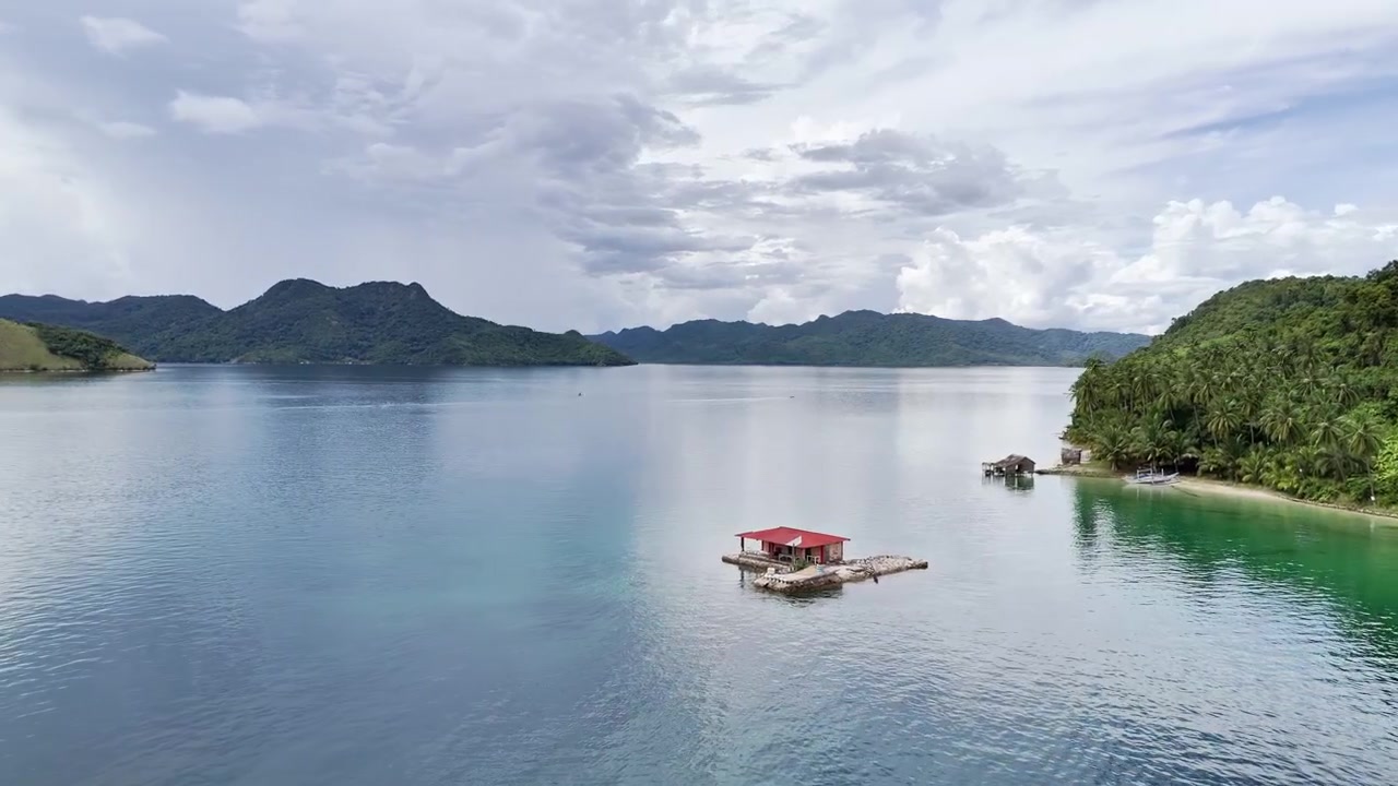 Piccola casa su un banco di sabbia vicino alla costa dell'isola. Filmato a San Jose, Taytay, Palawan, Filippine. Il drone avanza ed esegue una leggera panoramica per rivelare le acque turchesi e l'ambiente costiero