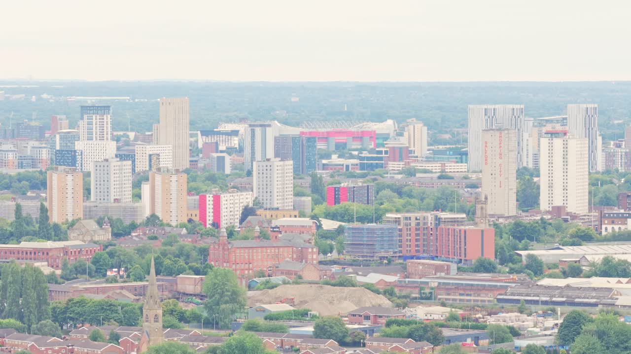 Lo skyline di Salford e Manchester presenta moderni grattacieli, edifici con accenti rossi e lo stadio Old Trafford in lontananza, ripreso con una ripresa aerea ascendente con drone.