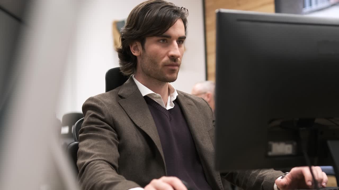 Focused young businessman using desktop PC in creative office