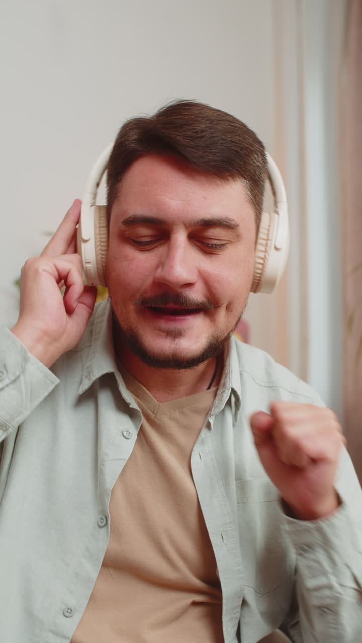 feliz relajado muy feliz joven caucásico en auriculares inalámbricos escuchando música en la habitación de casa