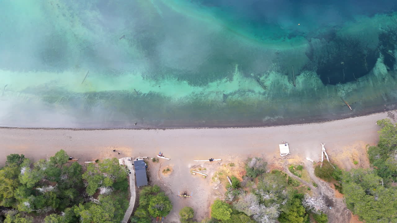 아르헨티나의 빌라 라 앙고스투라에 있는 바야 만사 해변을 위에서 내려다보며 황금색 모래와 생생한 푸른 물 사이의 아름다운 대조를 보여줍니다.