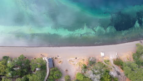 a stunning top-down aerial view of bahía mansa beach in villa la angostura, argentina, showcasing the beautiful contrast between golden sands and the vivid turquoise waters.