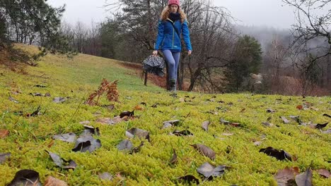 wide-shot,-woman-with-umbrella-in-hand-walking-on-a-meadow-hill-down-towards-camera