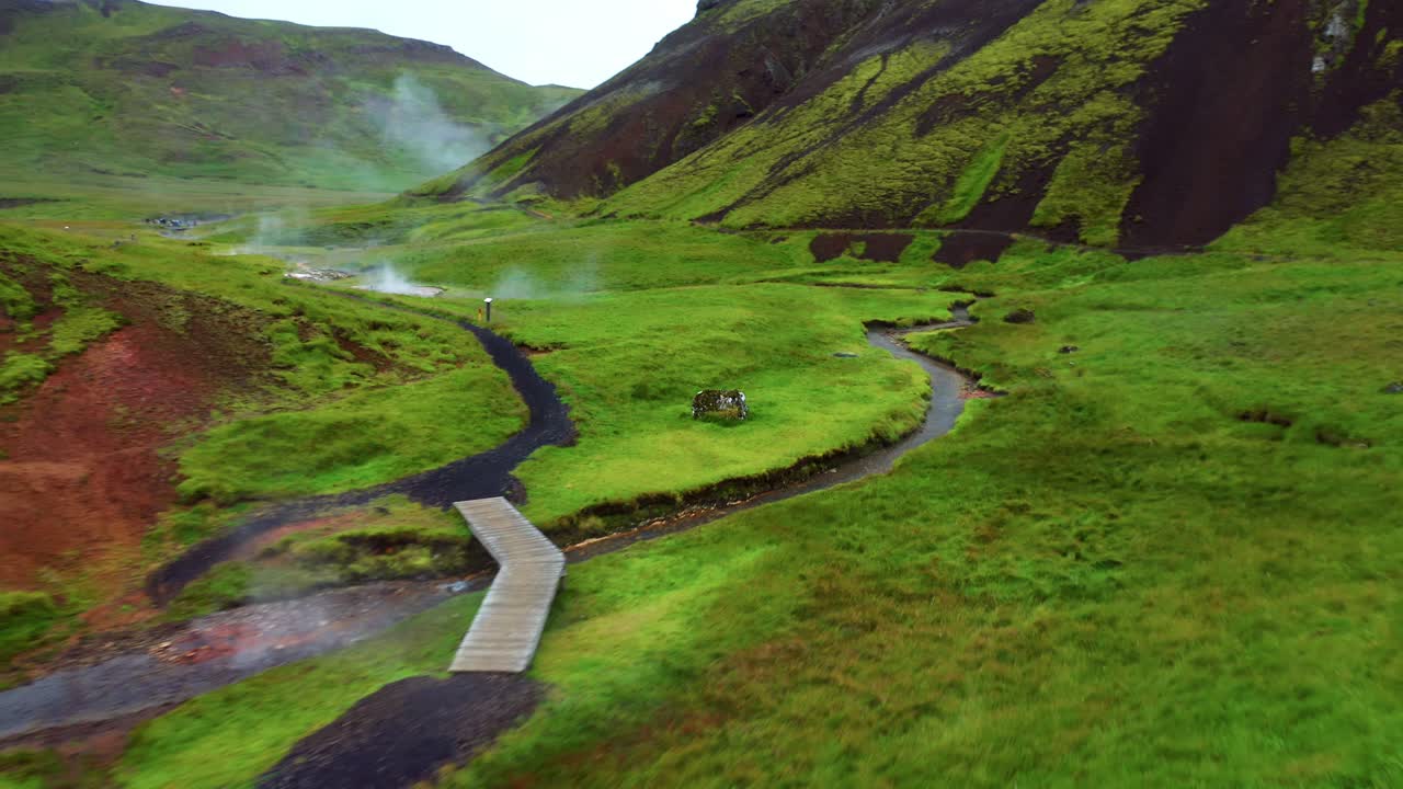 río angosto en medio de la pradera verde en el valle de reykjadalur en el sur de islandia