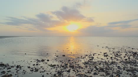 se eleva desde la costa de guijarros revelando un mar muy tranquilo durante la puesta de sol en cámara lenta en fleetwood, lancashire, reino unido