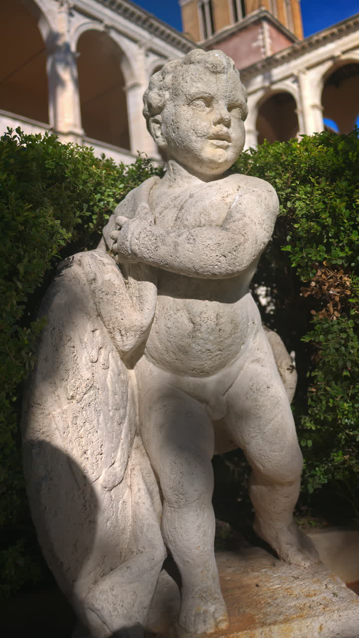 A cherub in the garden of the Basilica of St Mark Evangelist at Campidoglio. Rome, Italy. Vertical