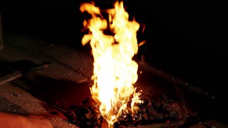 la mano del herrero calentando la vara de hierro en el fuego