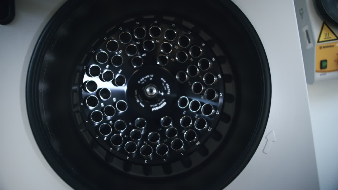 현대 면역학 실험실에서 공허한 의료 생화학 기술 원심분리 장비를 검사합니다.