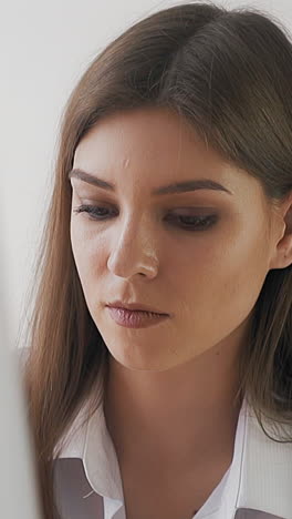 concentrated brunette woman art student in white blouse looks at canvas with new picture on wooden easel in light studio slow motion closeup