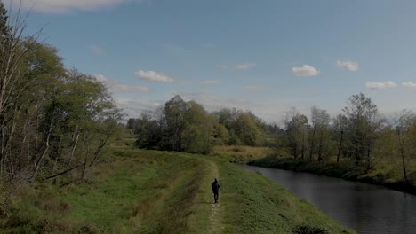 drone 4k footage cloverdale of a man walking on a dike levee trail in the rural backdrop with scenic terrain and revealing a highway in the distance