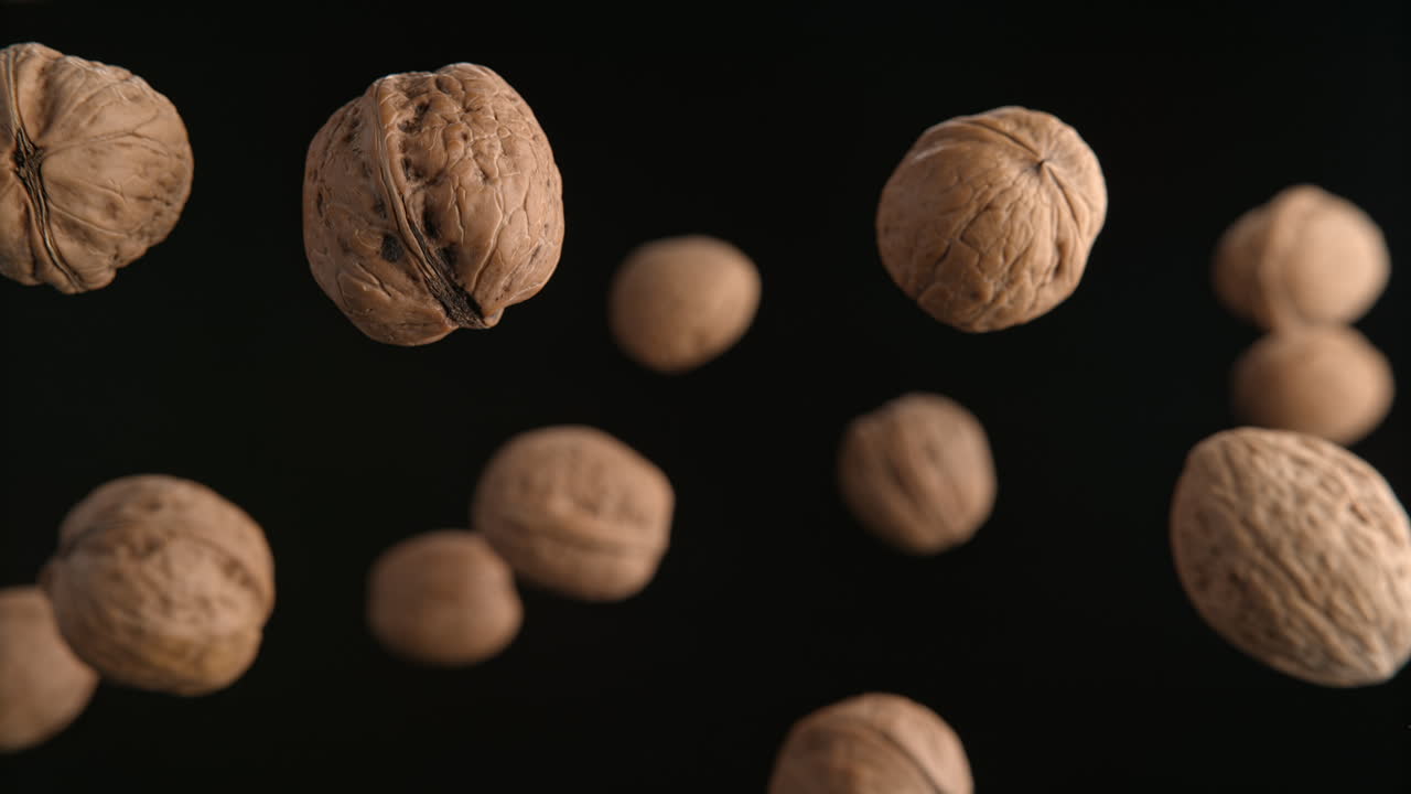 Walnuts In Shells Flying On The Black Background In Macro And Slow Motion