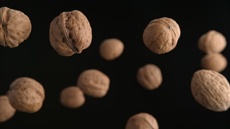walnuts in shells flying on the black background in macro and slow motion