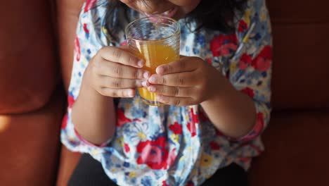 una niña linda disfrutando de un vaso de jugo de naranja
