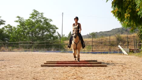 frontal view of a white horse and female rider threading between three ground bars with control