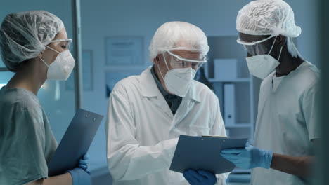 Team-of-Scientists-in-Protective-Uniforms-Discussing-Work-in-Lab