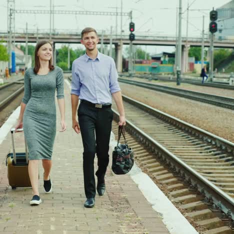 a young couple with bags goes on the platform at the station