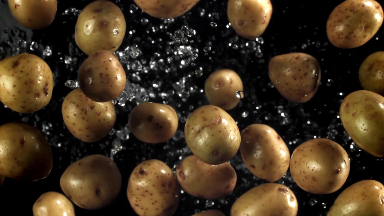 Patate fresche che cadono e creano schizzi d'acqua su sfondo nero