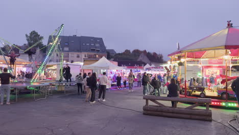 small funfair in montrichard val de cher at night with rides, people, and plush toy machines