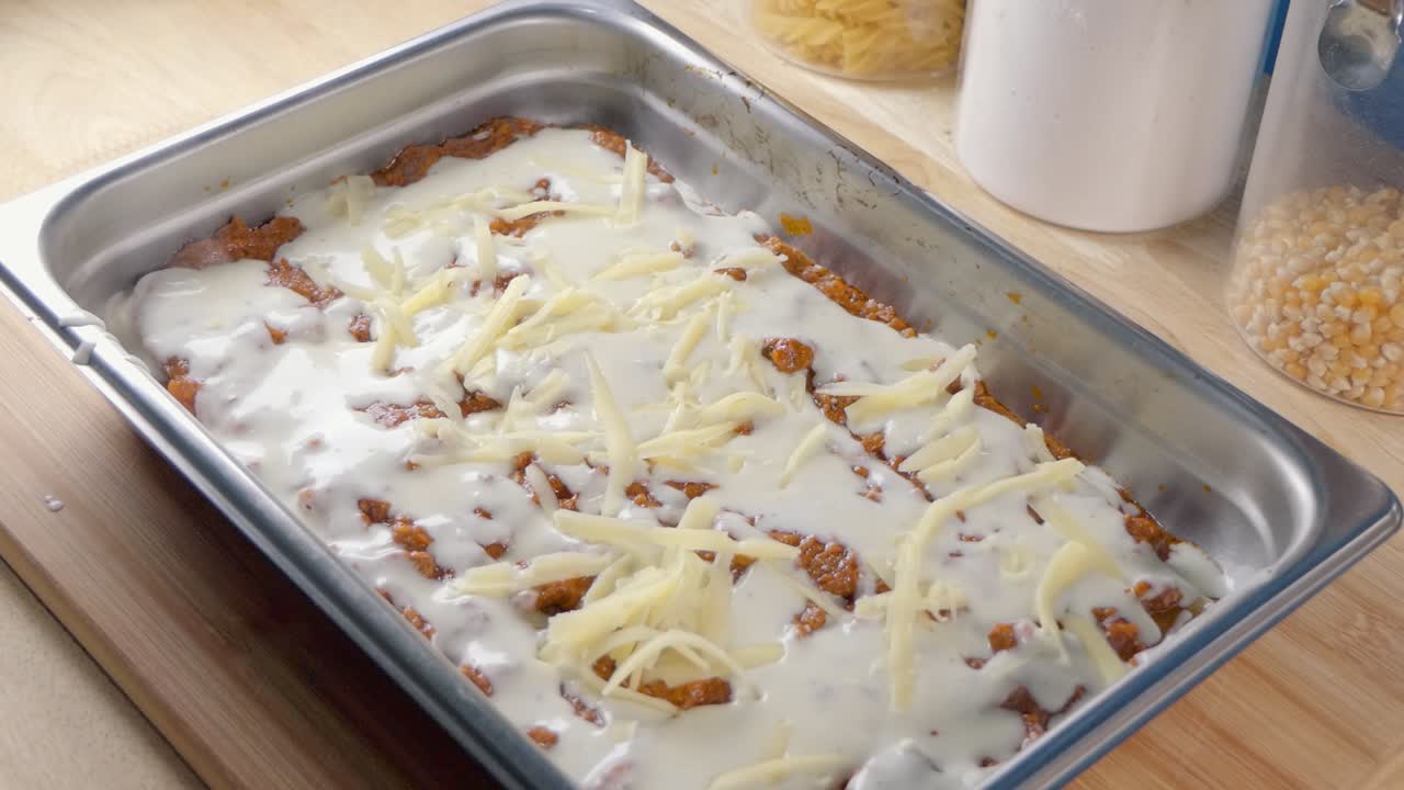 Medium Shot of Adding Freshly Grated Cheese to a Baking Tray for Making Lasagne