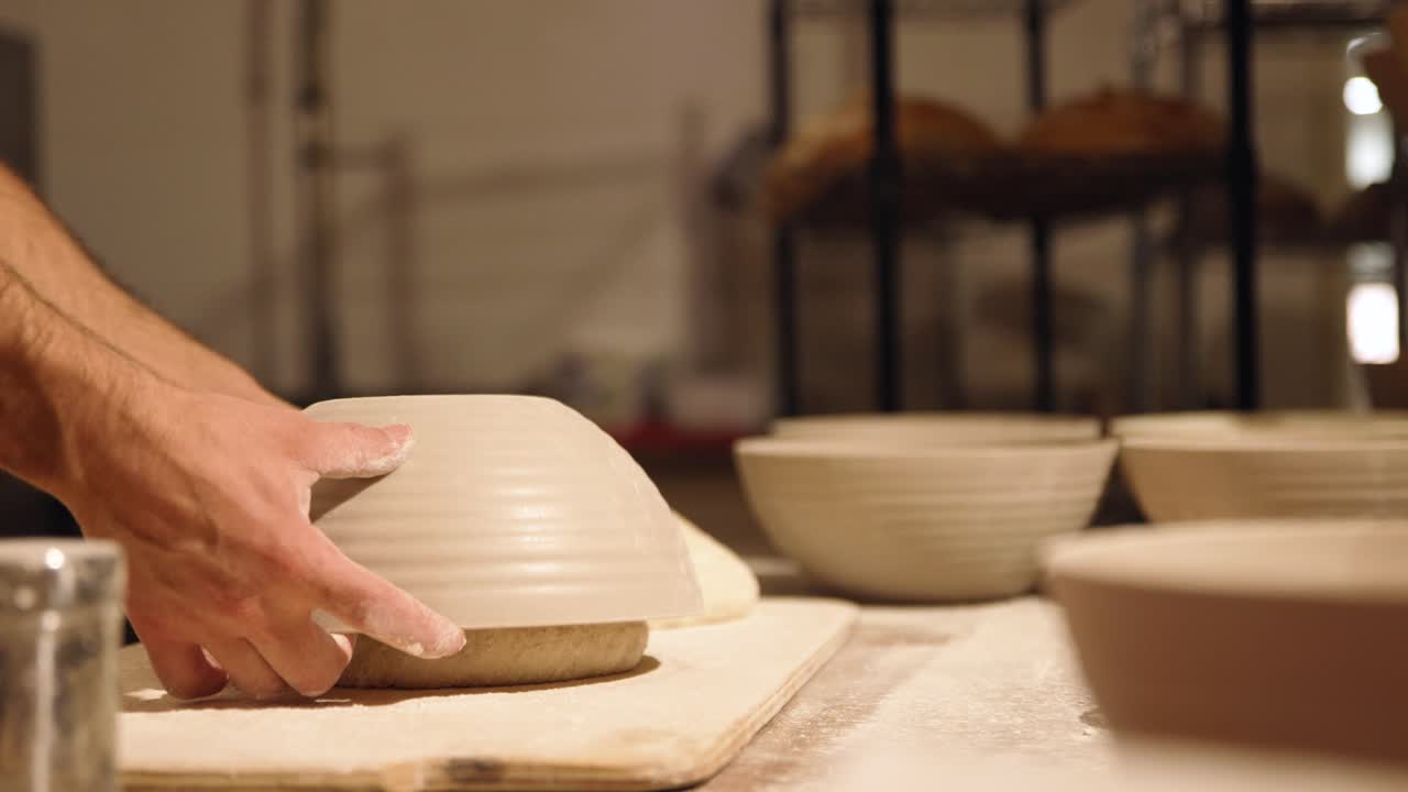 Baker's Hands Uncovering Proofed Bread Dough in a Bakery