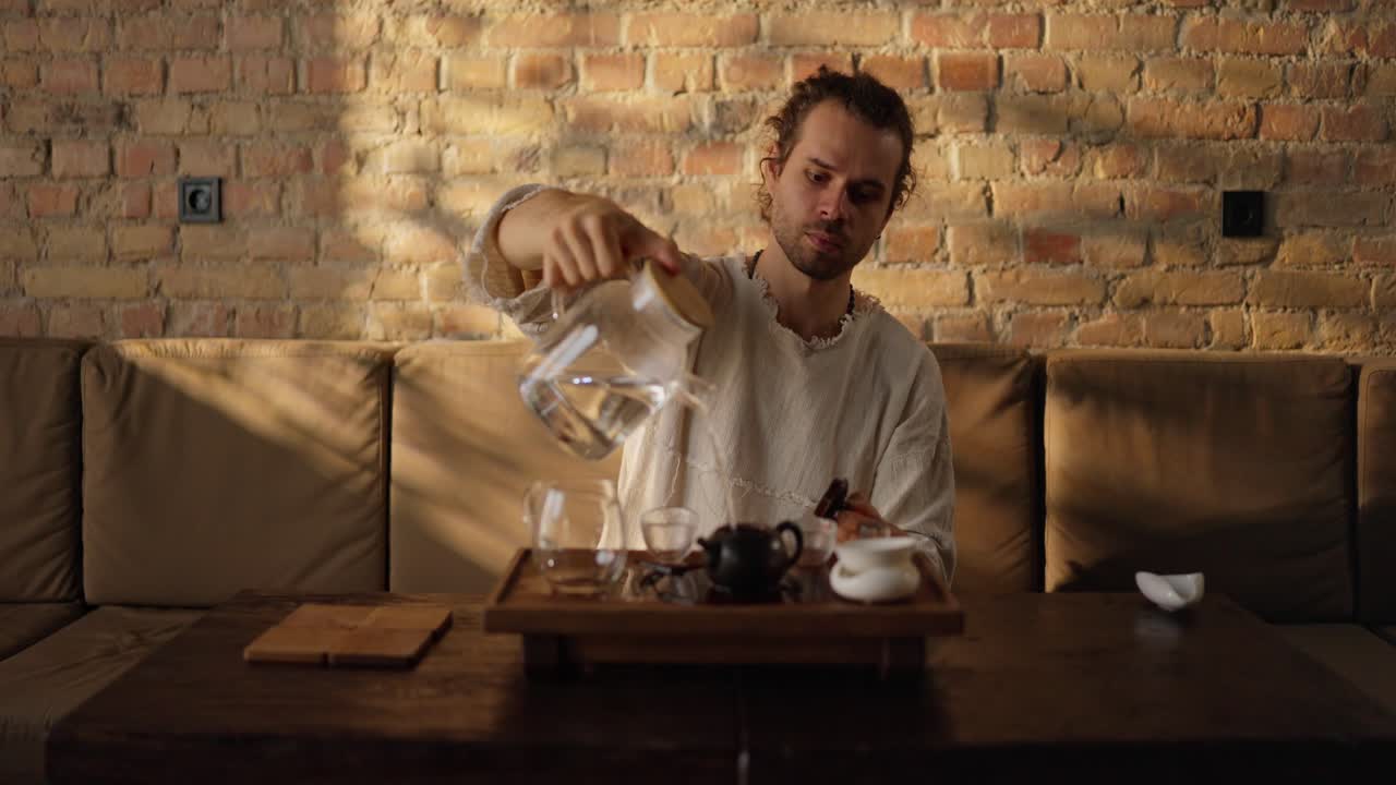 hombre vertiendo té de una tetera en una taza de té