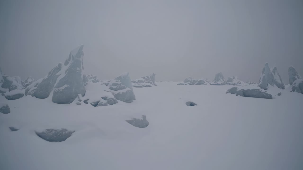 Wide-angle shot of a snowy landscape with scattered rocks, creating a serene, minimalist winter