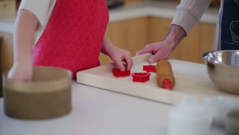 young boy helps dad bake christmas cookies with cookie cutters close up