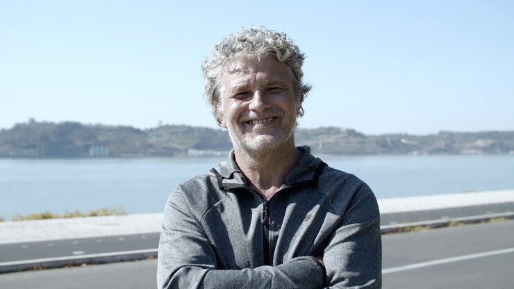 Cheerful active elder 60s man in sportswear standing outdoors